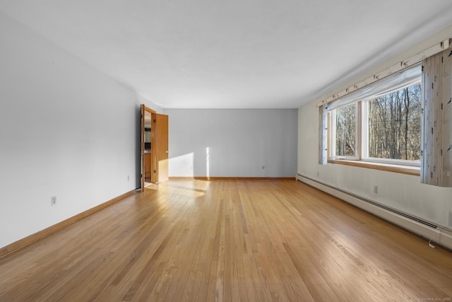 spare room with light wood-style floors, a baseboard radiator, and baseboards