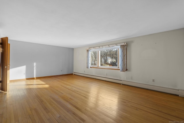 unfurnished living room with a baseboard heating unit, baseboards, and hardwood / wood-style floors