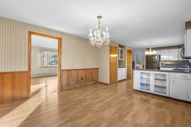 kitchen with a chandelier, baseboard heating, wainscoting, freestanding refrigerator, and wallpapered walls