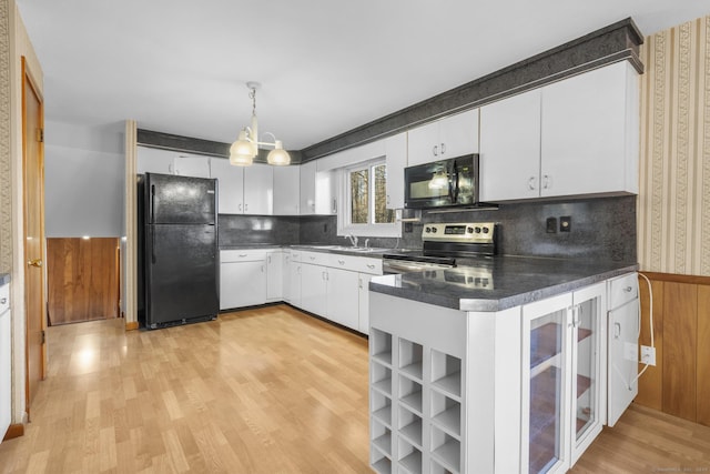 kitchen with light wood-style flooring, white cabinets, a peninsula, and black appliances