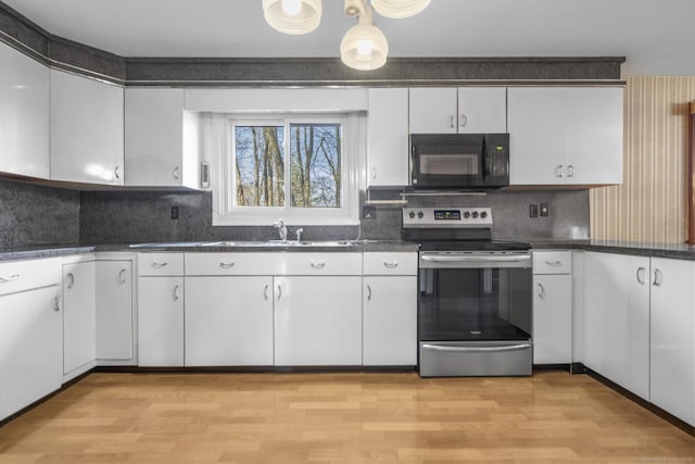 kitchen with black microwave, light wood-style flooring, stainless steel electric stove, white cabinetry, and a sink