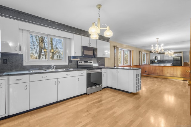 kitchen featuring dark countertops, black appliances, white cabinets, and a notable chandelier