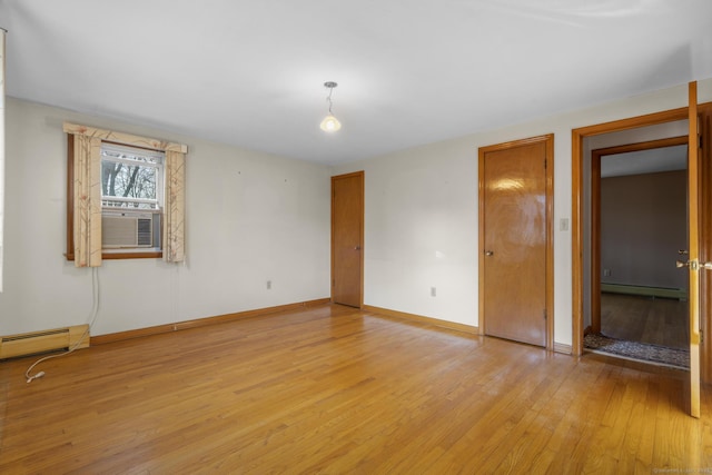 unfurnished room with baseboard heating, light wood-style floors, a baseboard heating unit, cooling unit, and baseboards