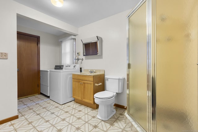 bathroom with washing machine and dryer, toilet, vanity, baseboards, and a stall shower