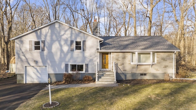 tri-level home featuring brick siding, a chimney, a garage, driveway, and a front lawn