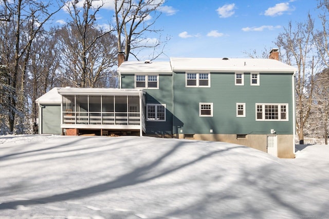 snow covered house featuring a sunroom