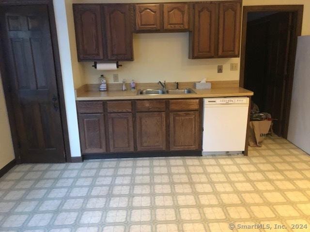 kitchen with white dishwasher, dark brown cabinets, and sink