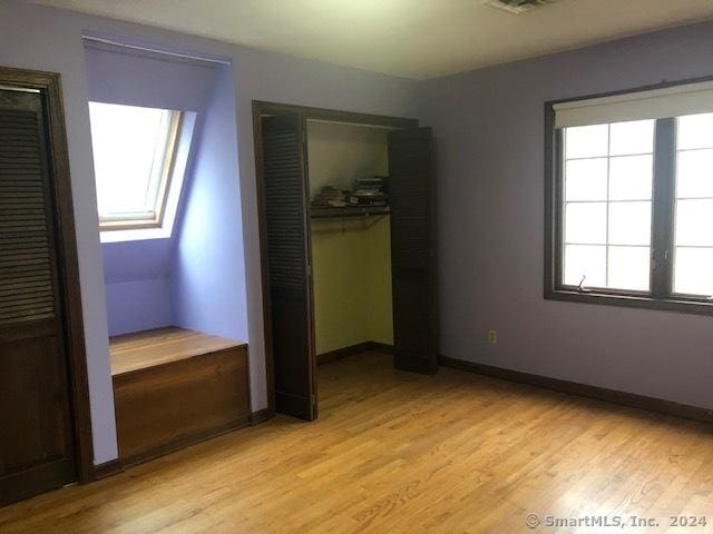 unfurnished bedroom with a skylight and light hardwood / wood-style flooring