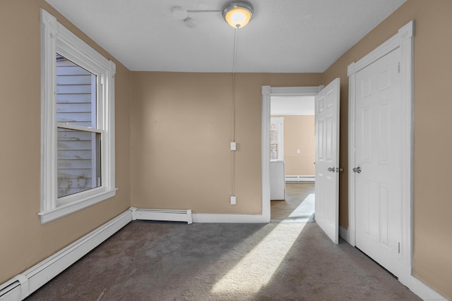 carpeted spare room featuring a baseboard heating unit