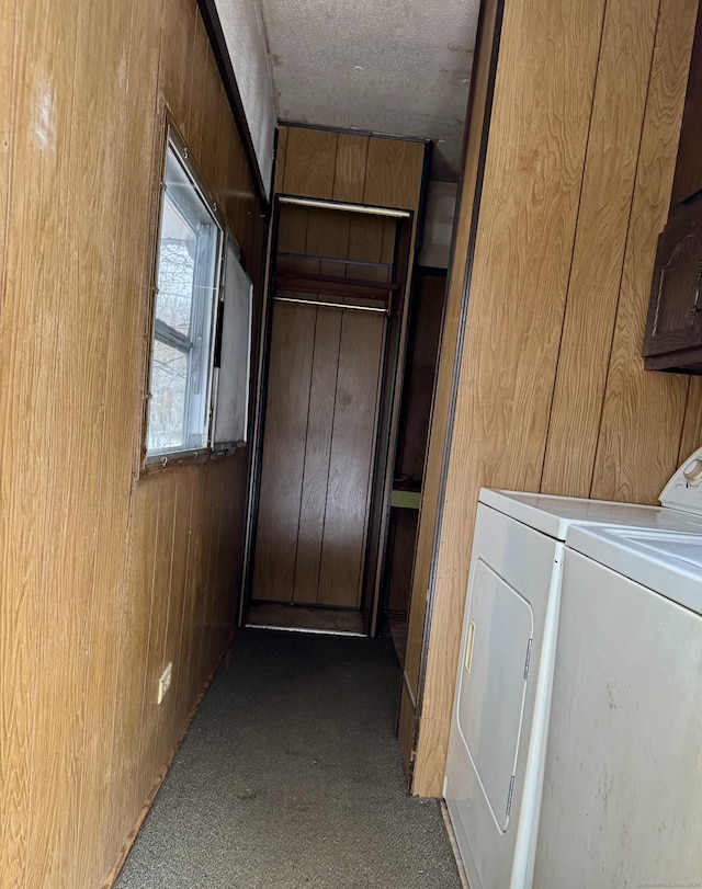 laundry area featuring wood walls, cabinets, washer and dryer, and a textured ceiling