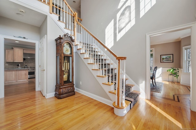 stairs featuring a high ceiling, hardwood / wood-style flooring, and ornamental molding