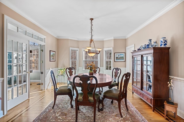 dining room with plenty of natural light, light wood-type flooring, crown molding, and an inviting chandelier