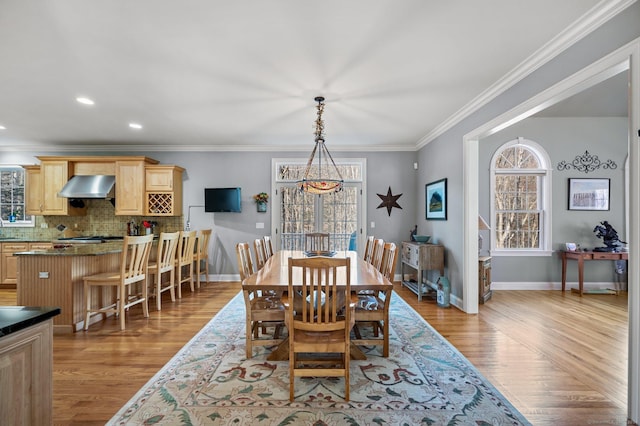 dining area featuring sink, light wood-type flooring, and crown molding