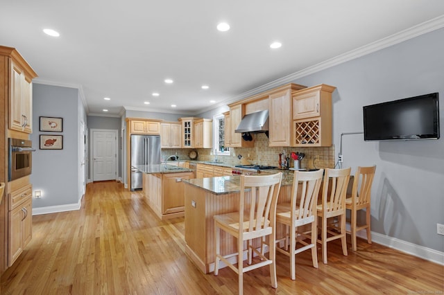 kitchen featuring a center island, wall chimney exhaust hood, light hardwood / wood-style floors, a breakfast bar area, and appliances with stainless steel finishes