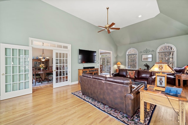 living room with ceiling fan with notable chandelier, wood-type flooring, high vaulted ceiling, and french doors