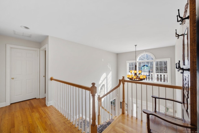 hallway with a chandelier and light wood-type flooring