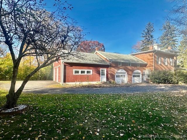 view of side of property featuring driveway, a yard, and a garage