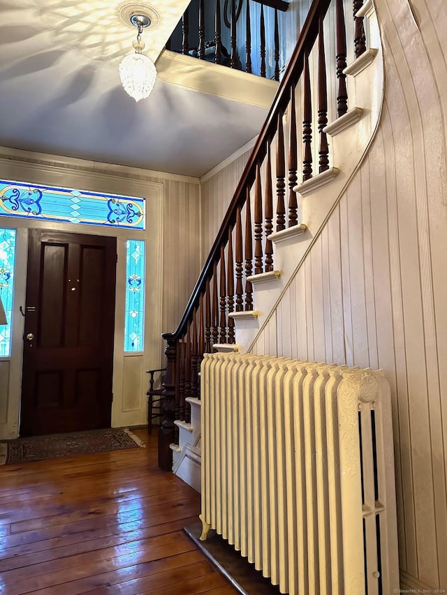 entryway featuring wood walls, wood-type flooring, and radiator heating unit