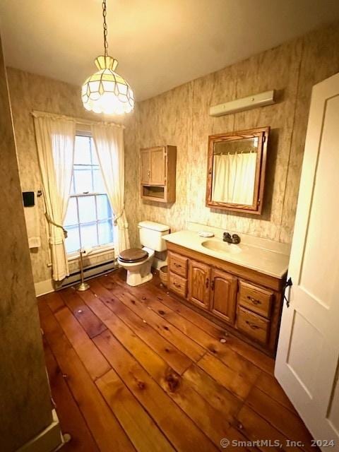 bathroom with wood-type flooring, vanity, toilet, and a baseboard heating unit