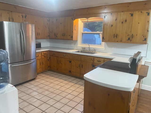 kitchen featuring kitchen peninsula, sink, light tile patterned floors, and stainless steel appliances