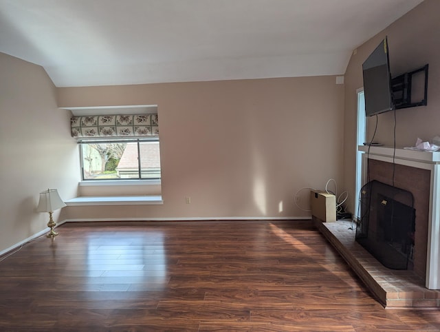 unfurnished living room with dark wood-type flooring, lofted ceiling, and a brick fireplace