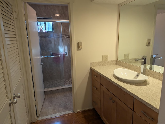 bathroom with wood-type flooring, vanity, and an enclosed shower