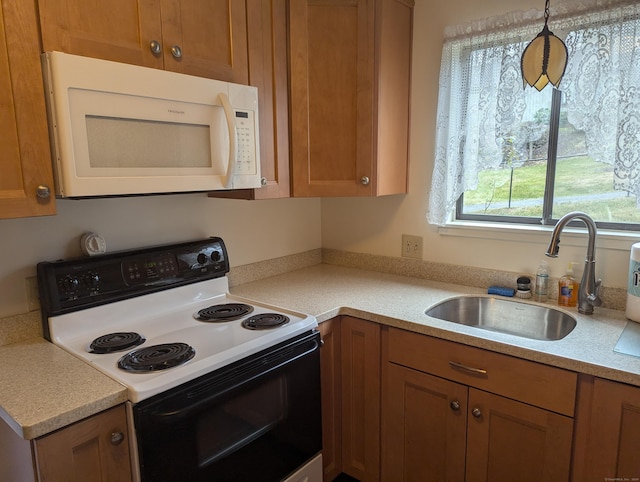 kitchen with pendant lighting, white appliances, and sink