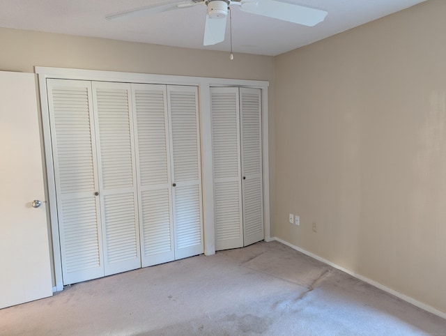 unfurnished bedroom featuring ceiling fan, light carpet, and two closets