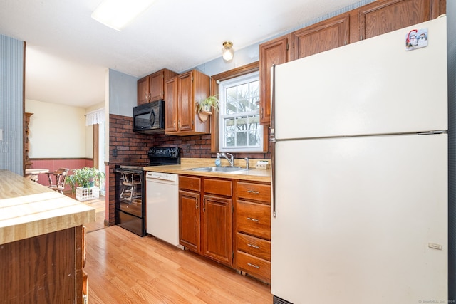 kitchen with tasteful backsplash, sink, light hardwood / wood-style floors, and white appliances