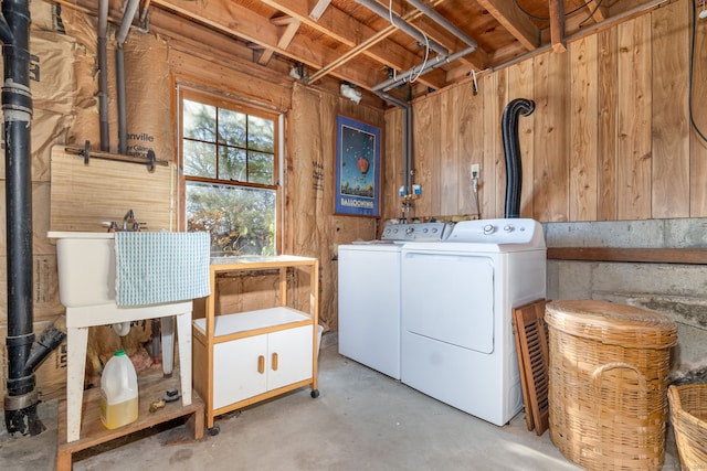 washroom with wood walls, separate washer and dryer, and sink