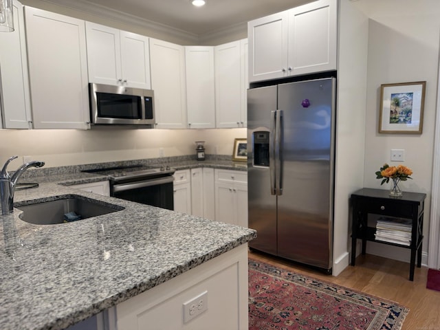 kitchen featuring white cabinetry, sink, light hardwood / wood-style floors, and appliances with stainless steel finishes