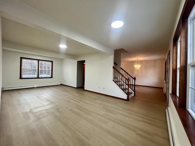 interior space with light wood-type flooring, a notable chandelier, and a baseboard heating unit