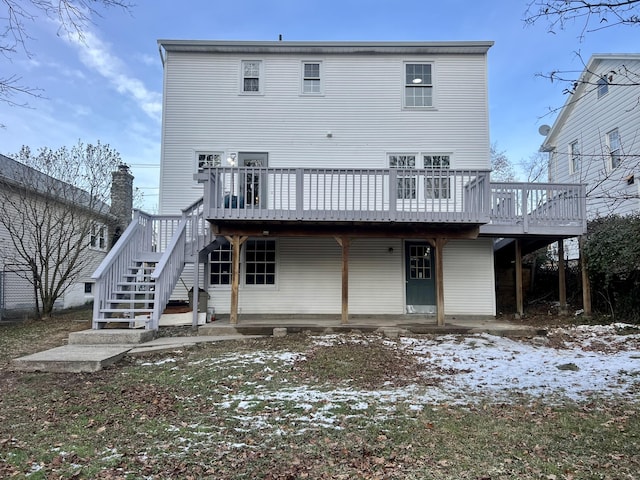 snow covered back of property featuring a wooden deck