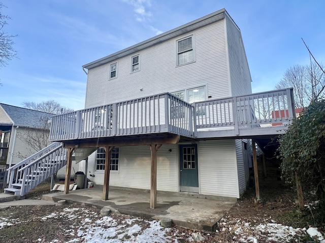 snow covered property with a patio and a wooden deck