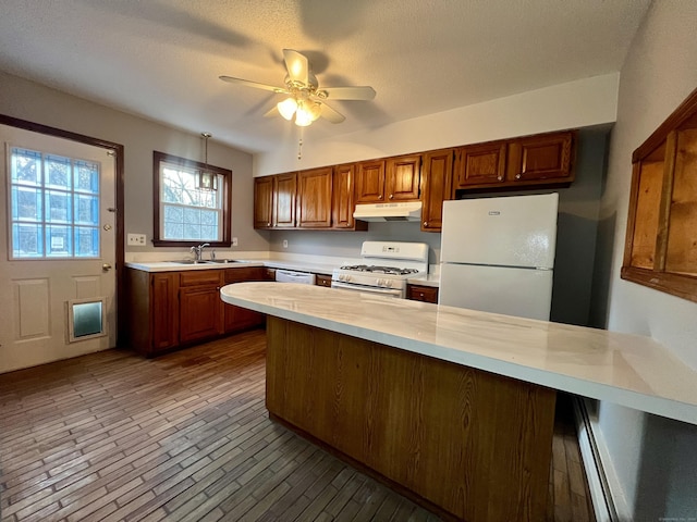 kitchen featuring white appliances, sink, hanging light fixtures, ceiling fan, and kitchen peninsula