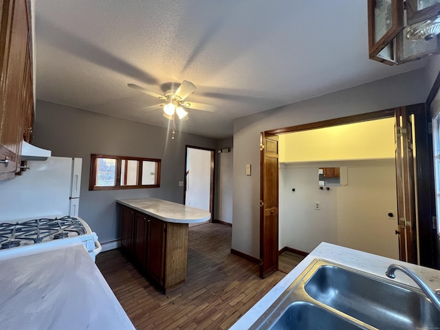 kitchen with white appliances, sink, dark hardwood / wood-style floors, a textured ceiling, and baseboard heating