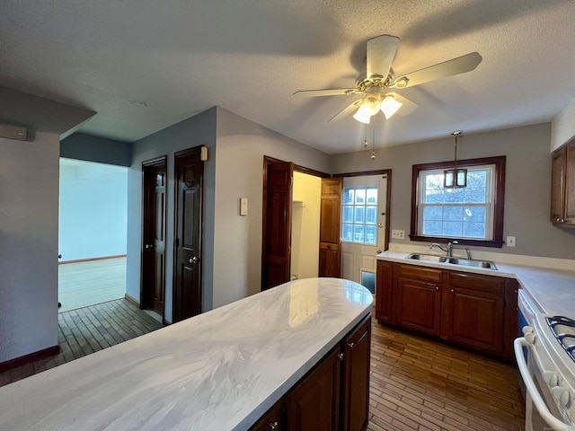 kitchen with gas range gas stove, ceiling fan, sink, decorative light fixtures, and dark hardwood / wood-style floors