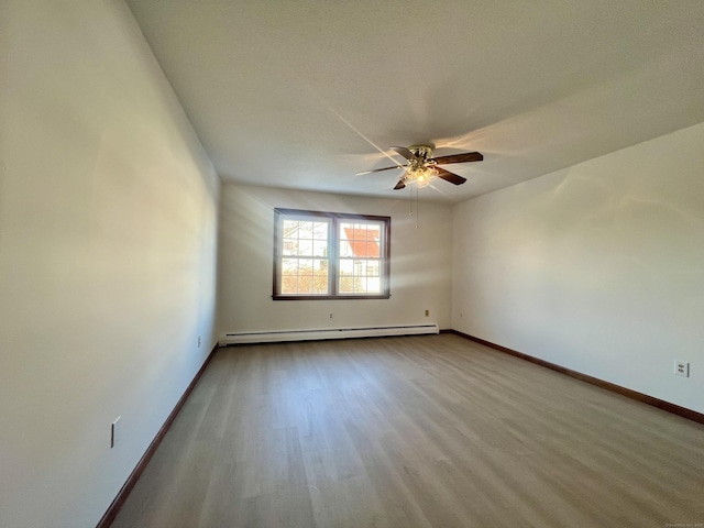 spare room featuring light hardwood / wood-style flooring, baseboard heating, and ceiling fan