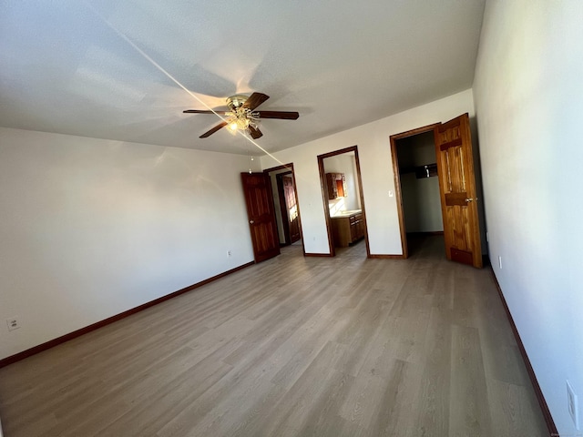 unfurnished bedroom featuring a textured ceiling, ceiling fan, light wood-type flooring, and ensuite bathroom