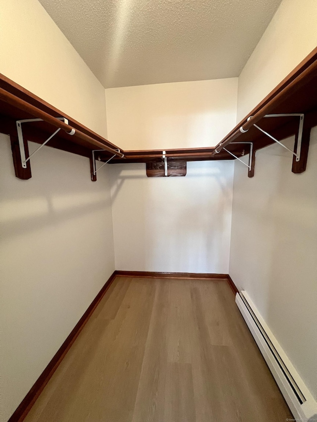 spacious closet featuring hardwood / wood-style floors and a baseboard radiator