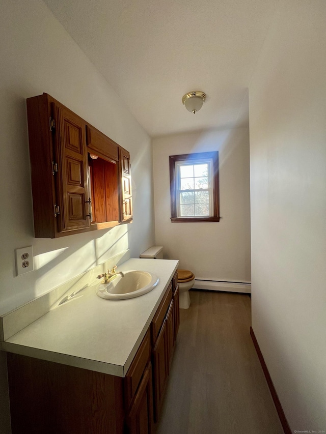 bathroom with hardwood / wood-style floors, vanity, toilet, and a baseboard heating unit