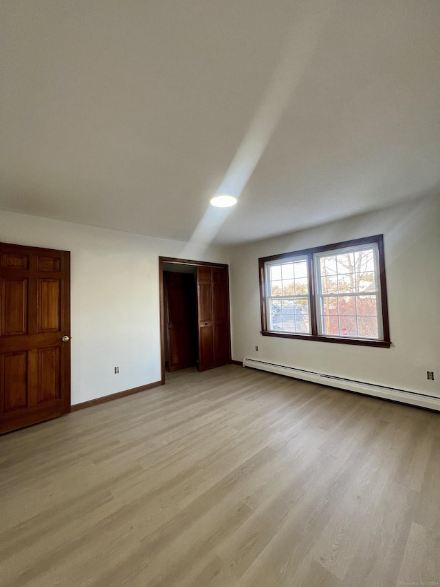 unfurnished bedroom featuring light wood-type flooring and baseboard heating