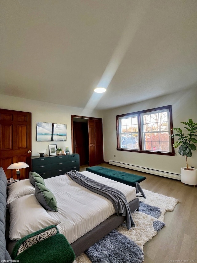 bedroom with light wood-type flooring and a baseboard heating unit