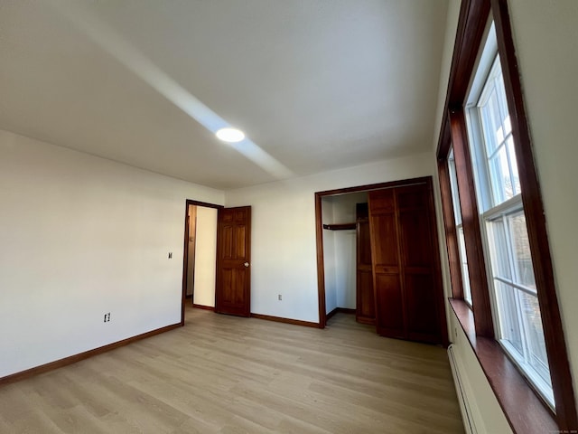 unfurnished bedroom featuring a closet, light hardwood / wood-style flooring, and a baseboard radiator