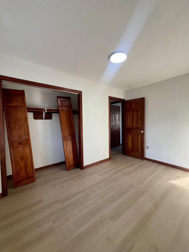 unfurnished bedroom with a textured ceiling, light hardwood / wood-style floors, and a closet