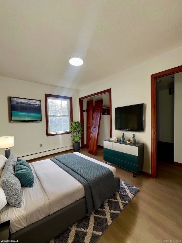 bedroom featuring hardwood / wood-style floors and baseboard heating