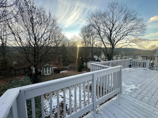 deck at dusk featuring a storage shed