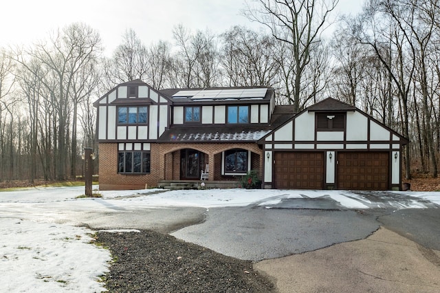 tudor house with solar panels, a garage, and covered porch