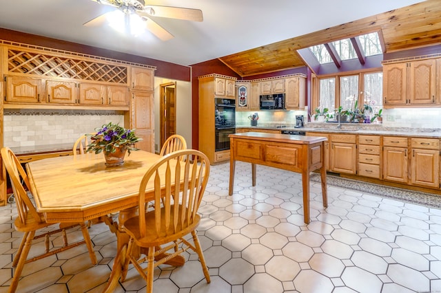 kitchen featuring lofted ceiling with skylight, black appliances, sink, decorative backsplash, and ceiling fan