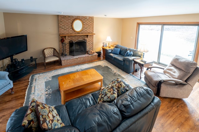 living room with a brick fireplace and hardwood / wood-style flooring